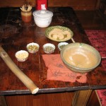 To make lui cha, pound tea leaves, nuts, and seeds in a bowl with a stick.